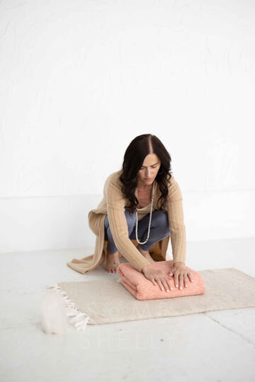 A woman meticulously folds a yoga mat, preparing it for use in a retreat
