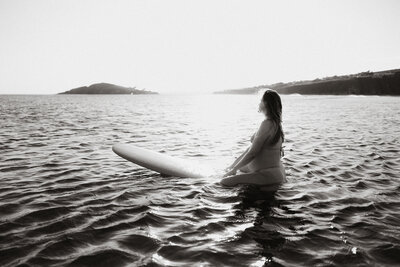 portrait of a pregnant woman on a surfboard in the sea
