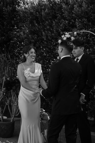Bride and groom standing at the alter together, in black and white.