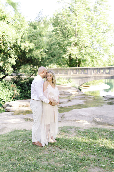 Pregnant woman and husband in beautiful park by a pond