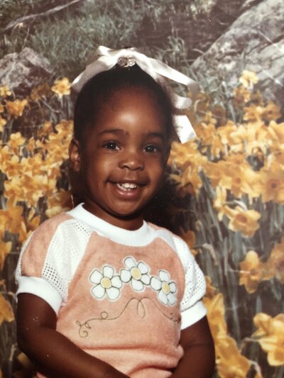 little girl smiling in front of yellow flowers