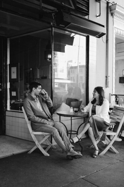 black and white artistic photograph of a couple sitting at a cafe in the city enjoying a glass of wine together