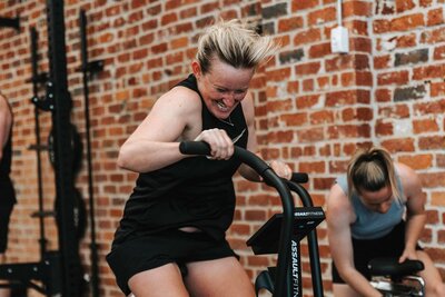 Blonde woman training hard on a bike in 24 hours dog friendly gym in Melbourne