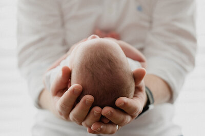 Dad holds newborn baby's head in his hands