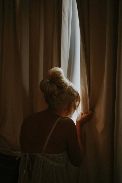 Bride peeking through blids at her wedding