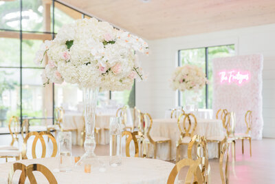 a white table with gold chairs and a pink and white floral centerpiece