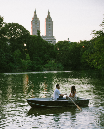 A couple looking at each other, sitting in a rowboat on Central Park Lake. Medium format film