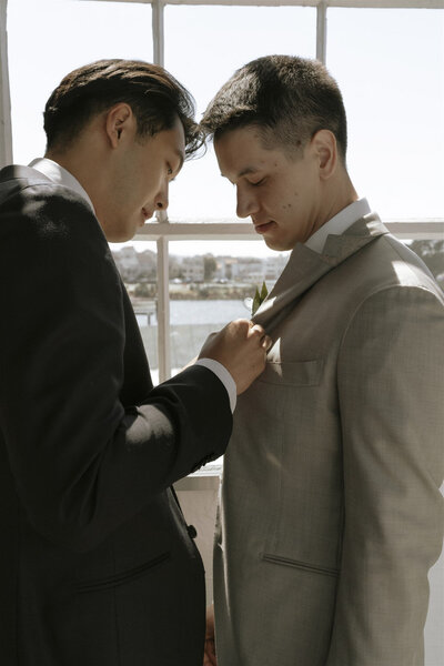 Groom adjusting partner’s suit before wedding