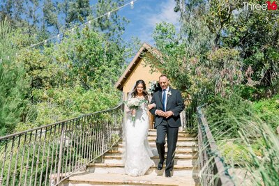 Bride and Groom stand on the stairs holding hands and gazing at each other at the Dove Canyon Courtyard in Trabuco Canyon