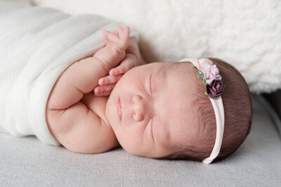 Newborn laying in nursery chair with flower headband - Family Photographer Nashville