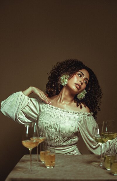 Curly brown hair, White off the shoulder shirt, Big earrings, Brown background