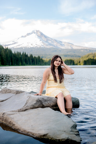 Girl sitting on rock at Trillium Lake with a view of Mount Hood.