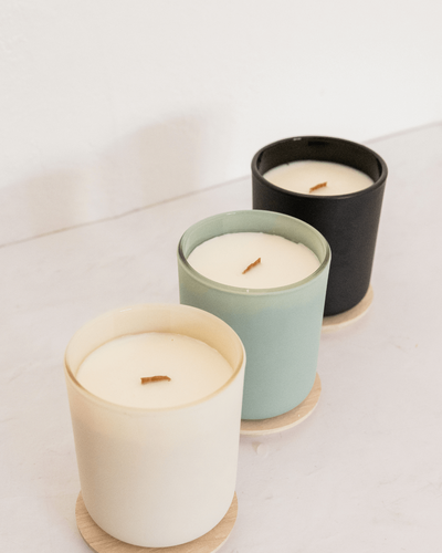 one white, one mint, and one black candle are all arranged from front to back on a white background