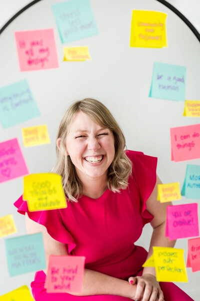 Kat Murphy smiling in a mirror covered in bright sticky notes