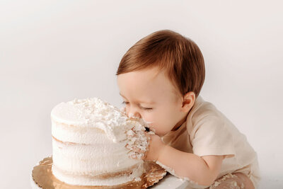 Portrait Photographers CT document precious cake smash moment as baby takes first bite during milestone birthday session