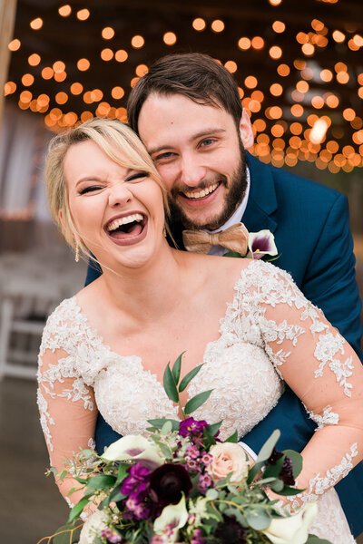 Bride and Groom laughing and cozy together at Grace Valley Farm with twinkle lights in background