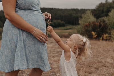 A pregnant women being photographed in Surrey fields on a summers day