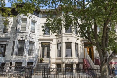 Beautiful townhouse in Brooklyn with a classic facade, gated entrance, and lush greenery