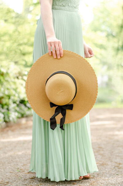 woman with green skirt holds summer hat