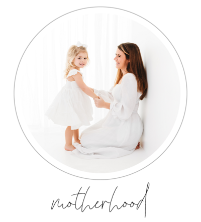 The photo depicts a heartwarming moment between a mom and her daughter. They pose together, both dressed in off-white dresses, for their motherhood portrait session in a stylish all-white studio. The image is captured by talented photographer Bri Sullivan, showcasing their natural beauty and the bond they share.