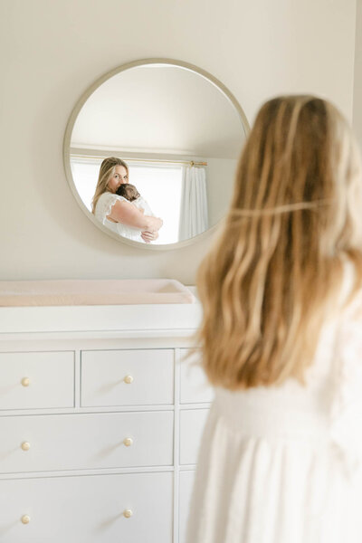 pregnant mother in white Baltic Born dress holds toddler in white linen dress over her baby bump during a maternity photo session  in Delaware with AnneMarie Hamant