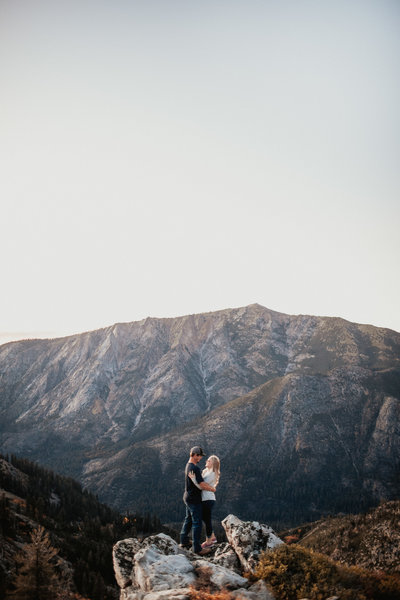 man and woman kissing in front of mountains