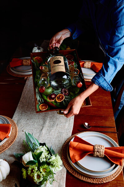 A vibrant and inviting image featuring Tito’s Vodka presented on a serving tray, surrounded by dried citrus garnishes. Captured by Mica McCook, this scene highlights the elegance and festive atmosphere of a well-crafted cocktail presentation.