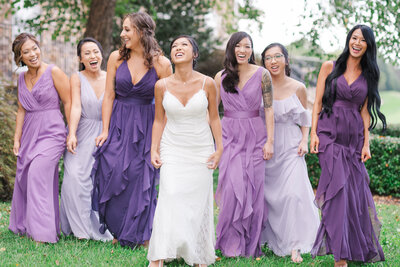 Bride and her Bridesmaids laughing and walking in their various shades of purple dresses photographed by Austin Tx based Wedding Photographer Lydia Teague