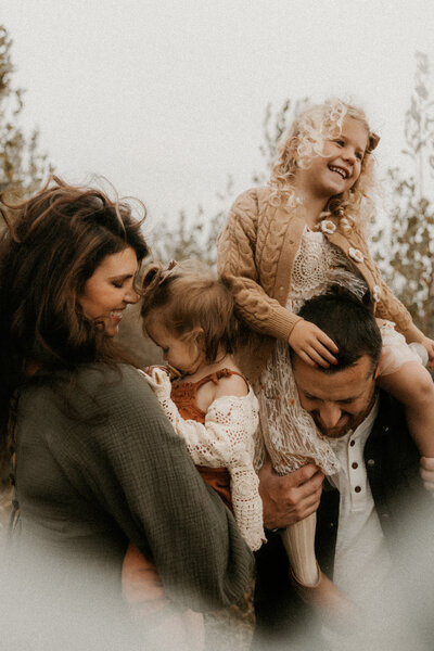 Photo of a family of four having fun at their photo session with their hair blowing in the wind.