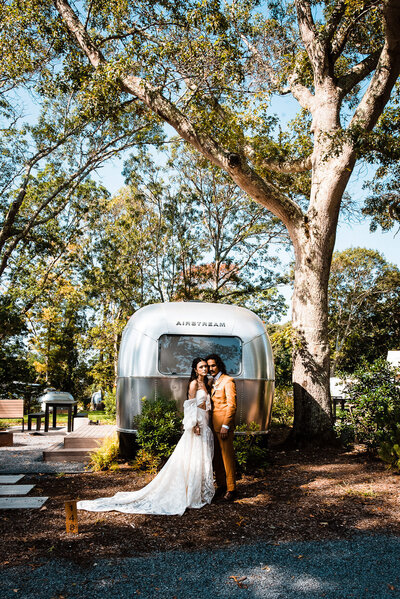 bride and groom stand near airstream