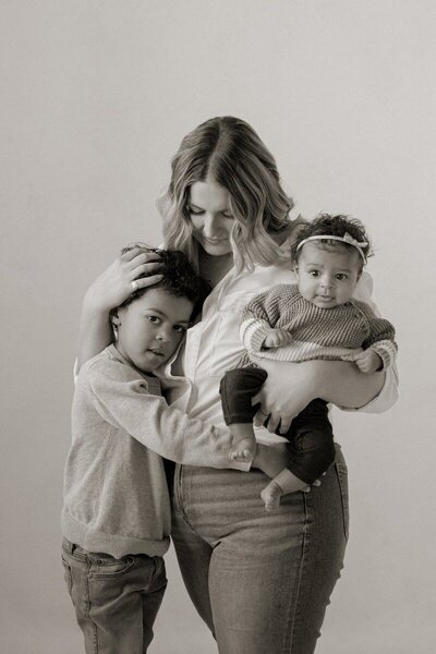 Mother holding two young children in studio captured by a Michigan photographer