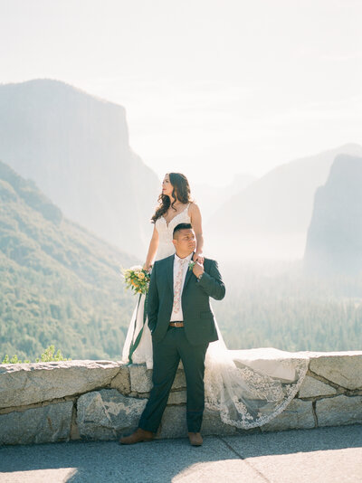 Lilac covered arch with bride in catheral veil and groom kissing in SoCal