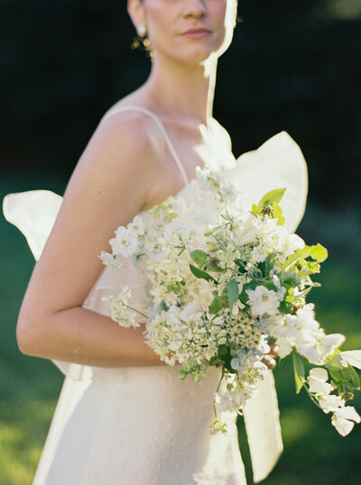 Modern coastal bride holding an elegant all-white bouquet at her timeless New England wedding, captured in natural light.