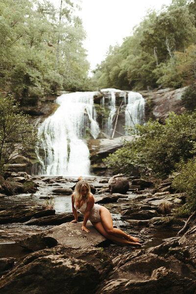 woman sitting in front of waterfall
