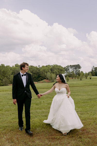 a bride and groom laughing togeher while they are walking together on their wedding day 