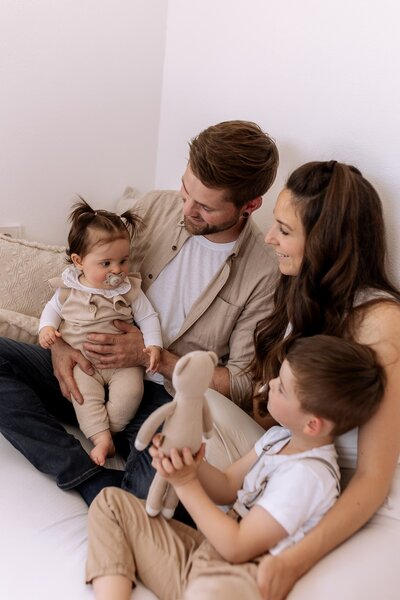 Eine Familie bestehend aus Vater, Mutter Sohn und Tochter sitzen gemütlich auf ihrem Sofa