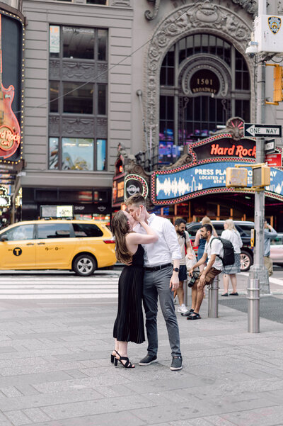 Engaged couple sharing a kiss in the middle of Times Square during their New York City engagement session.