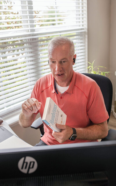 Mark Sullivan wearing a red shirt in his office coaching a client in his office while holding a book – Life and Health Coach at LifeNBalance Coaching26