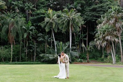 A newlywed couple kissing in the middle of a field 