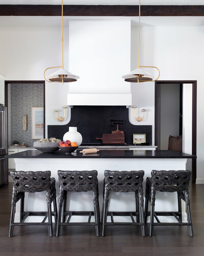 Kitchen island with brass lighting and rattan stools
