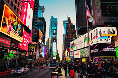A vibrant and bustling Times Square in New York City, filled with illuminated billboards, towering skyscrapers, and crowds of people soaking in the electric atmosphere. This iconic destination reflects the excitement and opportunities supported by vacation fundraising for charities.