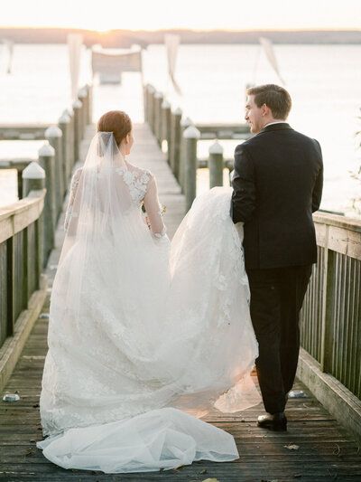 Bride and Groom walk on the docks of Inns of Aurora during a glowing sunset.