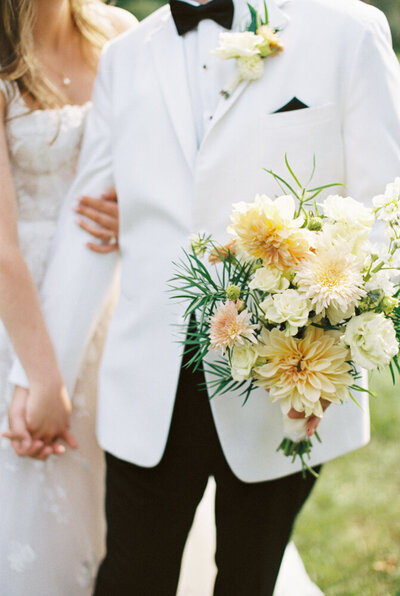 groom holding orange flowers