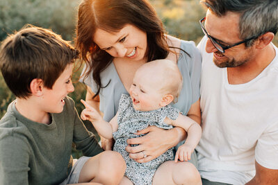 mom holding baby girl facing outward and smelling her head