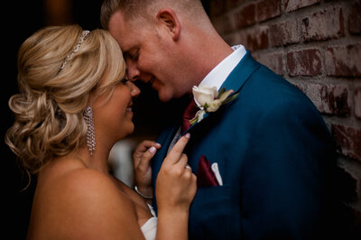 bride and groom leaning into each other about to kiss while bride holds hands on grooms chest