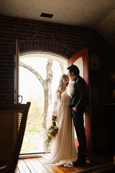 Bride and groom sharing a quiet moment near a doorway with natural light streaming in during their indoor Kentucky wedding.