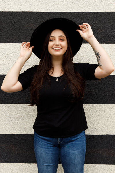 Headshot of Lucia, wearing a hat and smiling at the camera, owner of Lucia Giuseppina Photography.