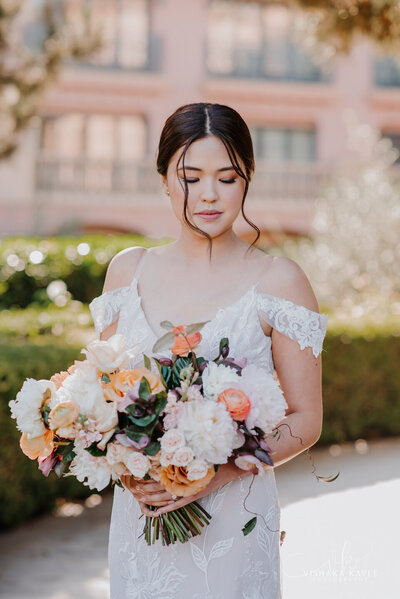 bride looking down while holding her bridal bouquet