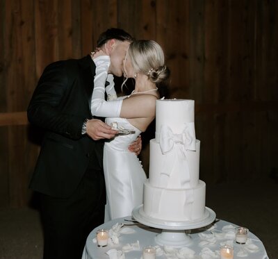 Bride and groom kissing before cutting their wedding cake