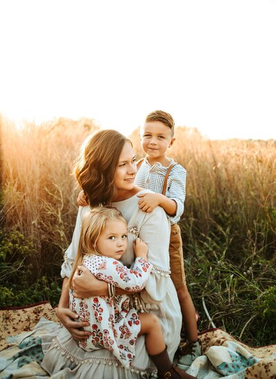 family portrait of a mother and her two children in a field